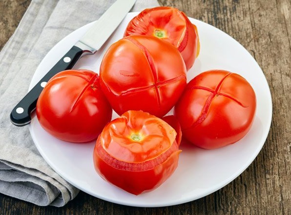 Dùng dao rạch vài đường trên quả cà chua rồi chần qua nước sôi cho dễ lột vỏ